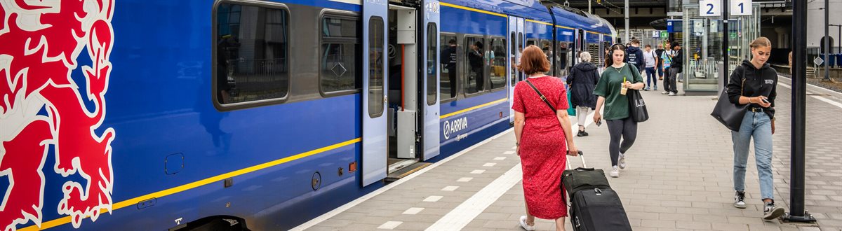 Reizigers op het perron van station Heerlen bij een Arriva-trein