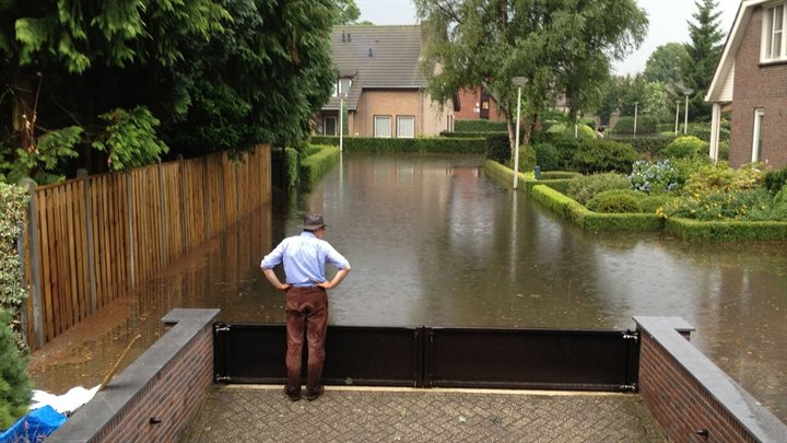 Een bewoner kijkt vanaf zijn oprit naar wateroverlast in de straat