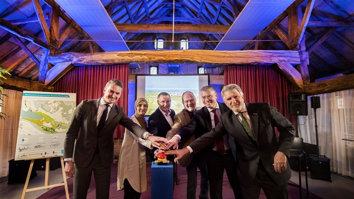 Bestuurders drukken op de knop, symbolisch als startsein voor de werkzaamheden aan de dijken in Well